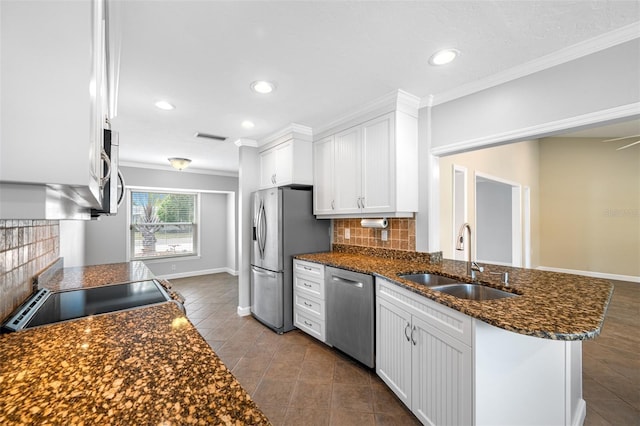 kitchen featuring appliances with stainless steel finishes, kitchen peninsula, decorative backsplash, white cabinets, and sink