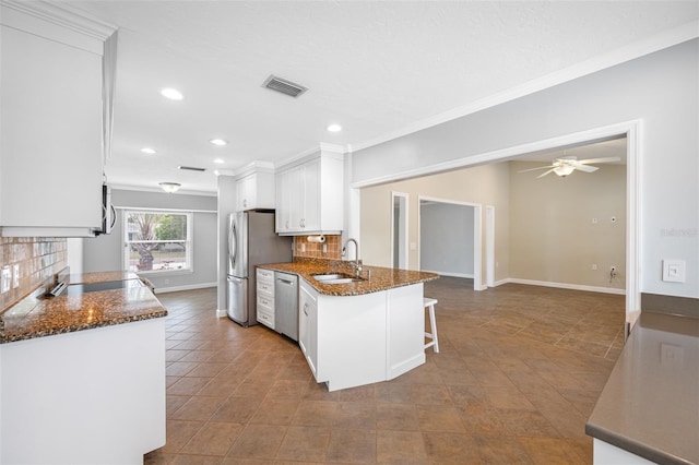 kitchen featuring sink, stainless steel appliances, white cabinetry, and kitchen peninsula