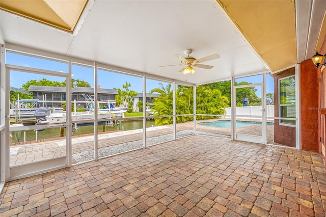 unfurnished sunroom with ceiling fan and a water view