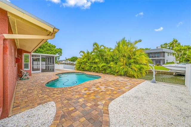 view of pool with a dock, a water view, a sunroom, and a patio area