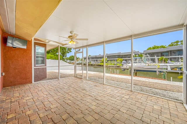 unfurnished sunroom with ceiling fan, a water view, and a wealth of natural light