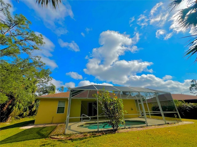 rear view of property featuring glass enclosure, a yard, and a patio area