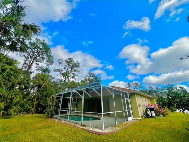 back of property with glass enclosure and a yard