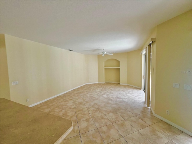 tiled spare room featuring ceiling fan and built in features