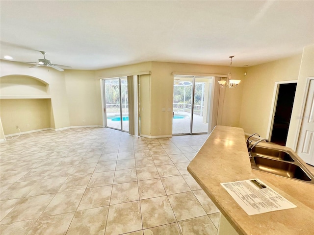 empty room featuring ceiling fan with notable chandelier, sink, and light tile patterned flooring