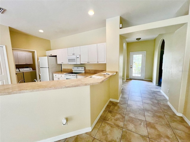 kitchen with kitchen peninsula, white cabinets, light tile patterned flooring, white appliances, and washer and clothes dryer