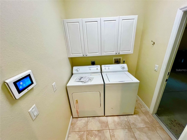 washroom featuring cabinets, washing machine and dryer, and light tile patterned flooring