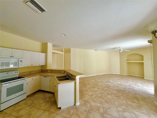 kitchen with kitchen peninsula, white appliances, sink, and light tile patterned floors