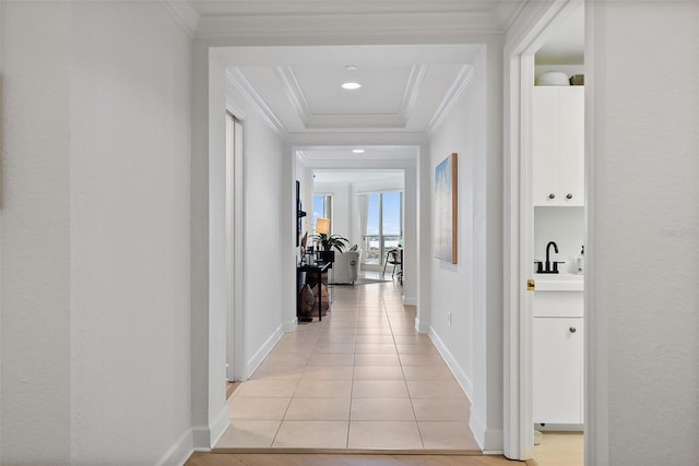 hallway with crown molding, sink, and light tile patterned floors