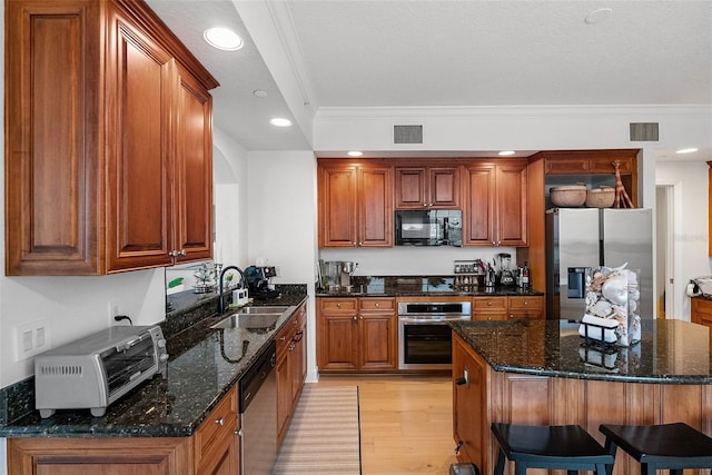 kitchen featuring sink, crown molding, dark stone counters, light hardwood / wood-style floors, and appliances with stainless steel finishes