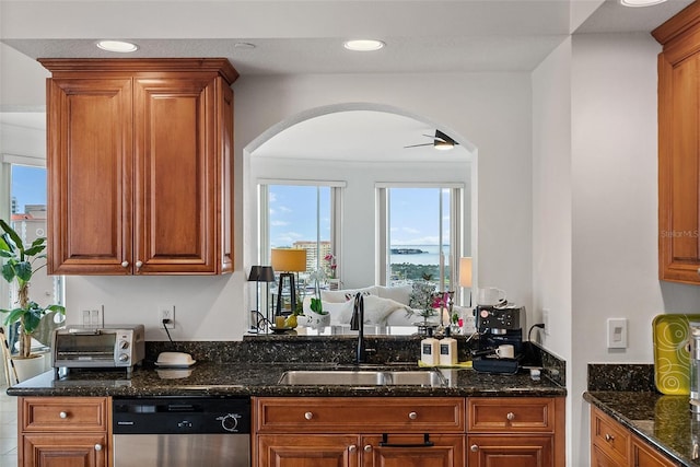 kitchen with dishwasher, ceiling fan, dark stone countertops, and sink