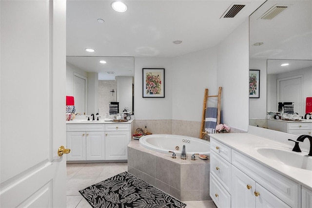 bathroom with tile patterned floors, vanity, and a relaxing tiled tub