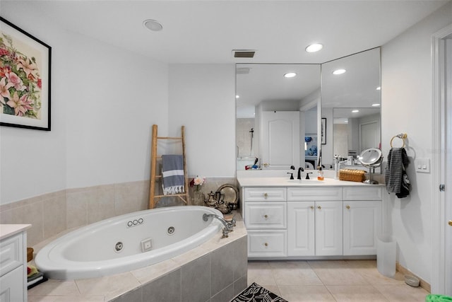 bathroom with tile patterned flooring, vanity, and tiled tub