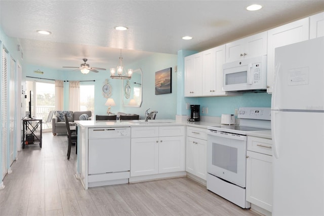 kitchen featuring kitchen peninsula, white appliances, pendant lighting, white cabinets, and sink