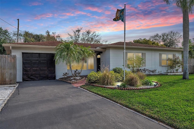 single story home featuring a lawn and a garage