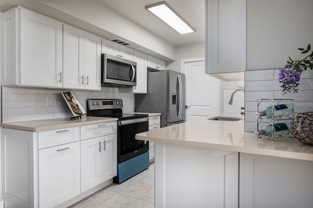 kitchen featuring backsplash, sink, stainless steel appliances, and white cabinetry