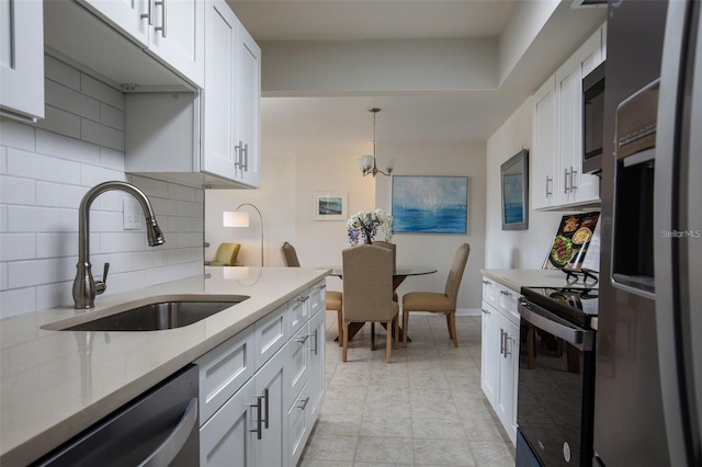 kitchen with decorative light fixtures, white cabinets, appliances with stainless steel finishes, and sink