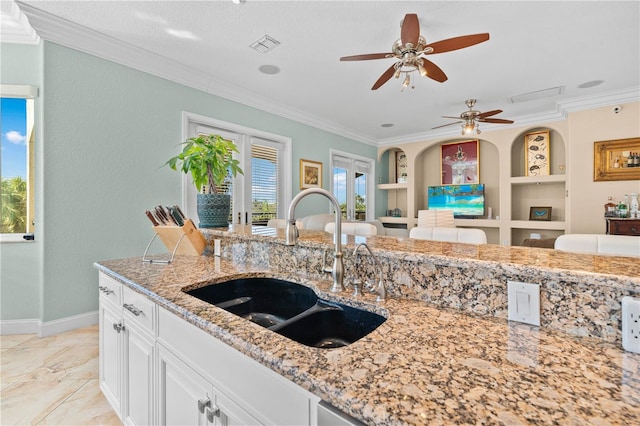 kitchen featuring ornamental molding, light stone countertops, sink, and white cabinets