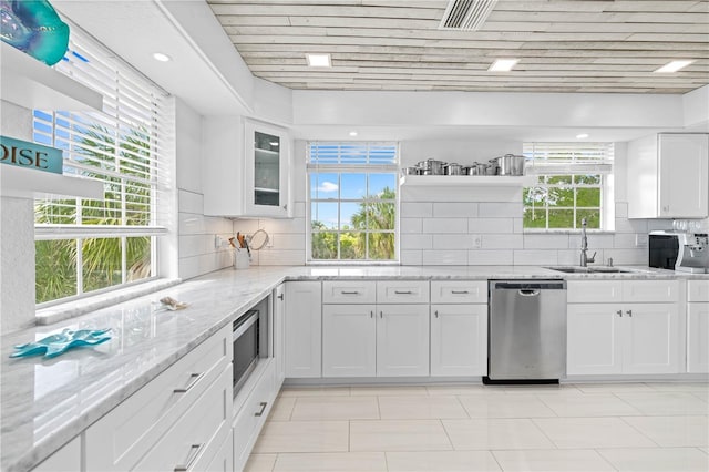 kitchen featuring appliances with stainless steel finishes, light stone countertops, sink, and white cabinets