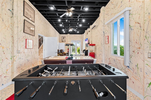 playroom featuring a ceiling fan, baseboards, a wealth of natural light, and a wall mounted air conditioner