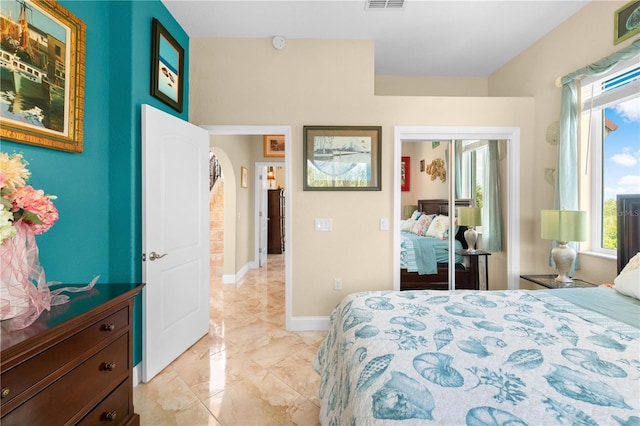 bedroom with a closet, visible vents, marble finish floor, baseboards, and arched walkways