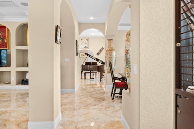 corridor featuring arched walkways, built in features, marble finish floor, baseboards, and ornamental molding
