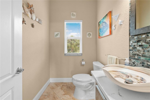 bathroom with tile patterned flooring, vanity, baseboards, toilet, and a textured wall