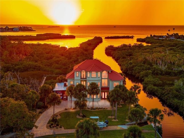 aerial view at dusk with a water view and a forest view
