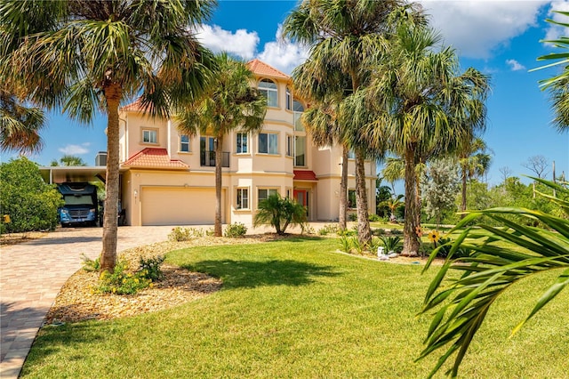 mediterranean / spanish-style house with a tile roof, a garage, stucco siding, a front yard, and decorative driveway