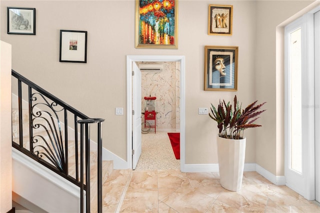 foyer entrance featuring baseboards, marble finish floor, and a wall mounted AC