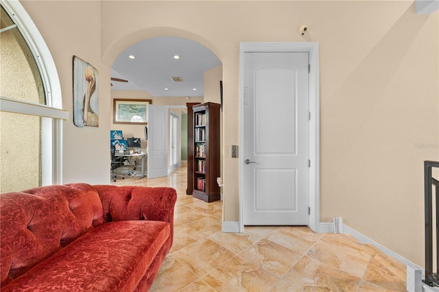living area with baseboards, arched walkways, visible vents, and recessed lighting