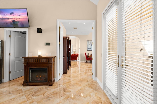 hallway featuring marble finish floor, lofted ceiling, baseboards, recessed lighting, and arched walkways