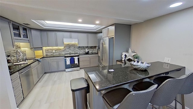 kitchen featuring gray cabinets, a kitchen breakfast bar, kitchen peninsula, and appliances with stainless steel finishes