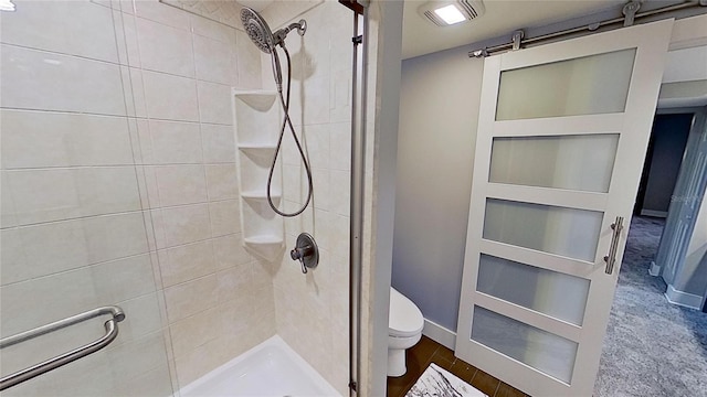 bathroom featuring tiled shower and toilet