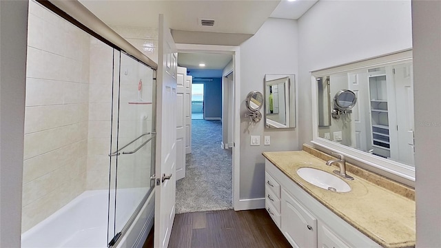 bathroom featuring hardwood / wood-style flooring, enclosed tub / shower combo, and vanity