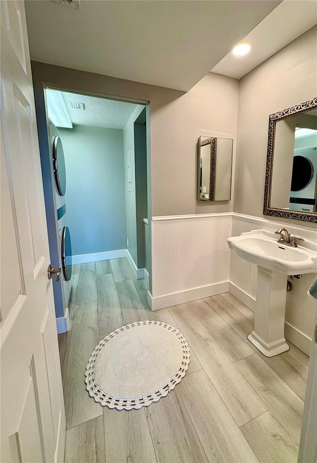 bathroom featuring wood-type flooring, stacked washing maching and dryer, and sink