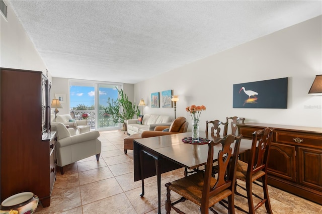 dining room with a textured ceiling, a wall of windows, and light tile patterned floors