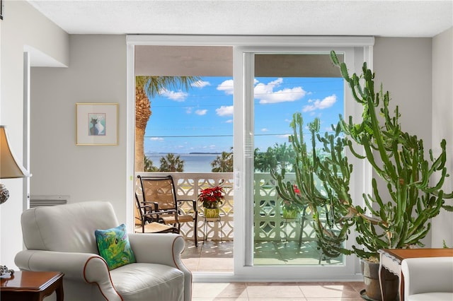 doorway with a textured ceiling, light tile patterned floors, and a water view