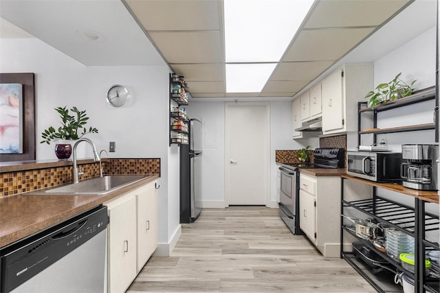 kitchen with appliances with stainless steel finishes, white cabinetry, sink, decorative backsplash, and a drop ceiling