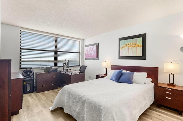 bedroom with a textured ceiling and light wood-type flooring