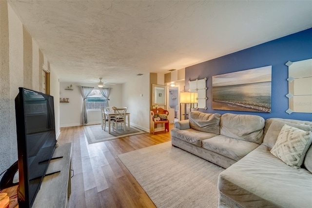 living room featuring ceiling fan, a textured ceiling, and hardwood / wood-style flooring