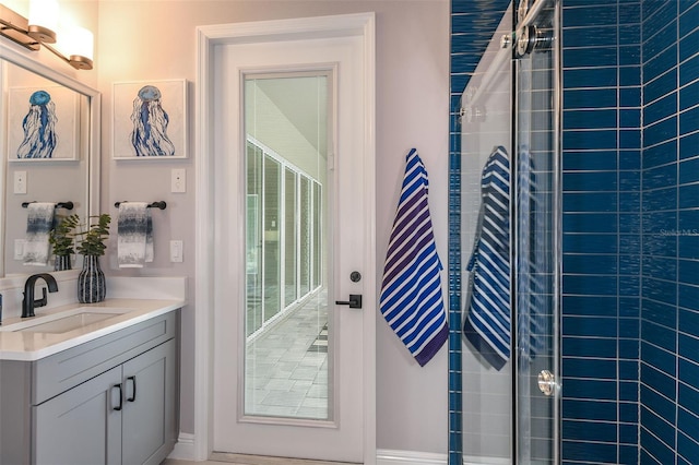 bathroom with a tile shower and vanity