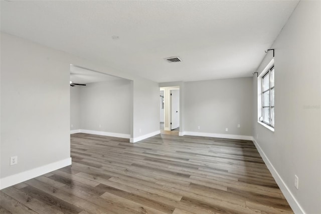 spare room featuring ceiling fan, light wood-type flooring, and a textured ceiling