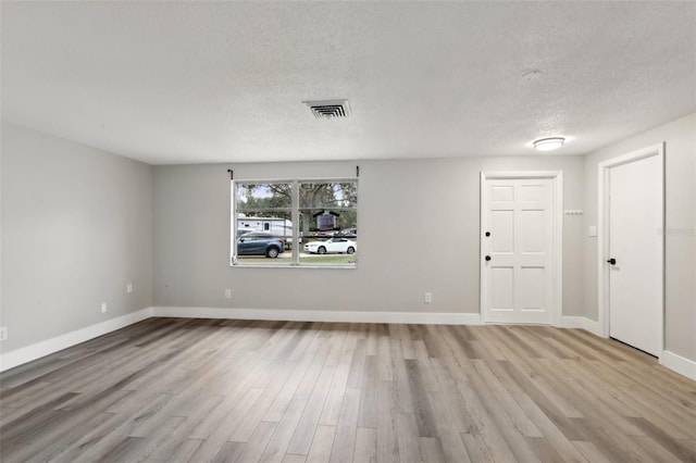 spare room with a textured ceiling and light wood-type flooring