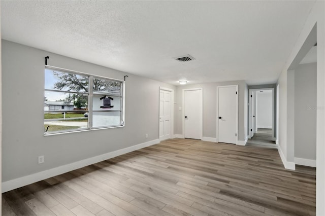 spare room with a textured ceiling and light wood-type flooring