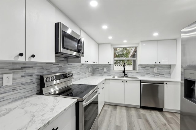 kitchen with decorative backsplash, sink, white cabinetry, and stainless steel appliances