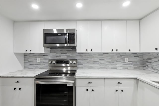 kitchen with light stone counters, backsplash, white cabinetry, and stainless steel appliances