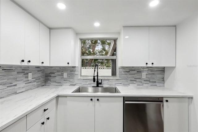 kitchen with stainless steel dishwasher, sink, tasteful backsplash, and white cabinetry