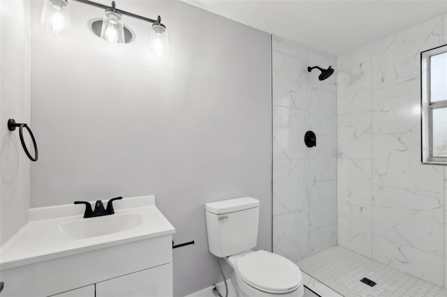 bathroom with toilet, vanity, and tiled shower