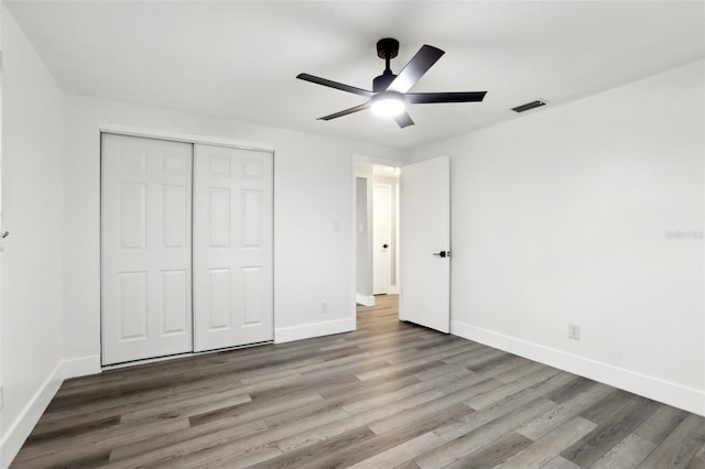 unfurnished bedroom with a closet, hardwood / wood-style flooring, and ceiling fan